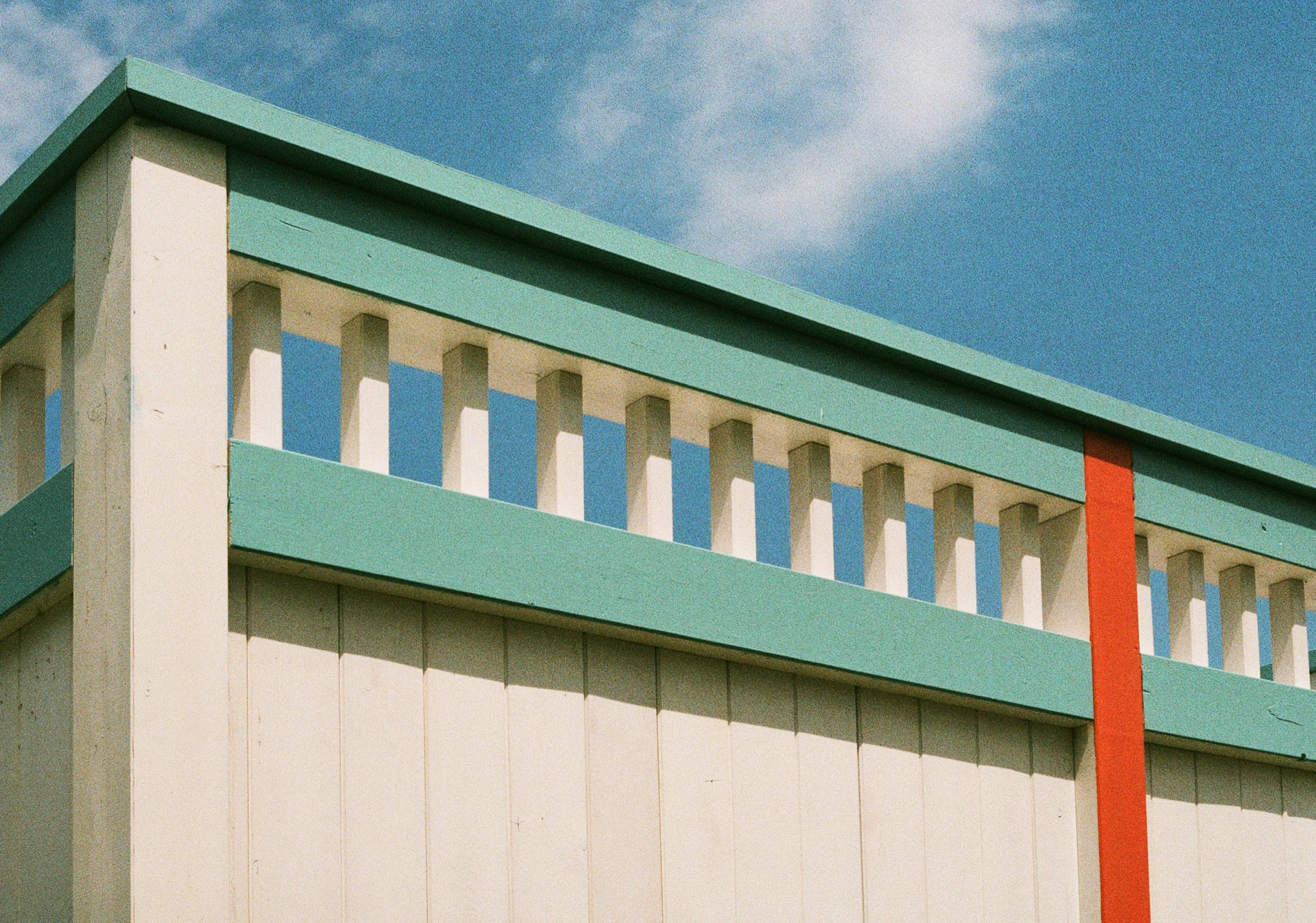 The mint and white parapet of a seaside building cut against deep blue sky